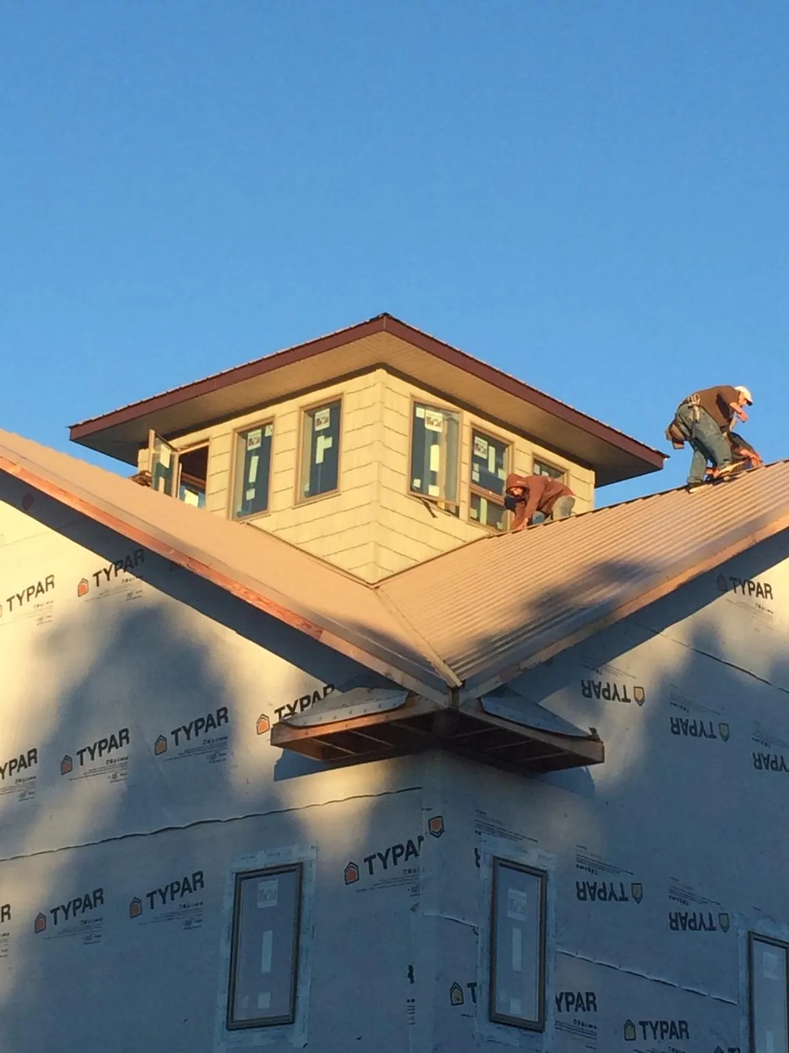 Roofers working around a rooftop cupola on a new metal roof at sunset — Roof Waterproofing in Winslow by Roofing Brothers